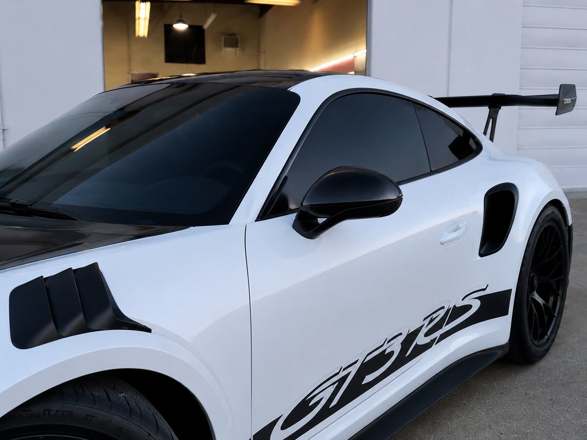 White Porsche 911 GT3 RS with dark tinted side glass outside the shop